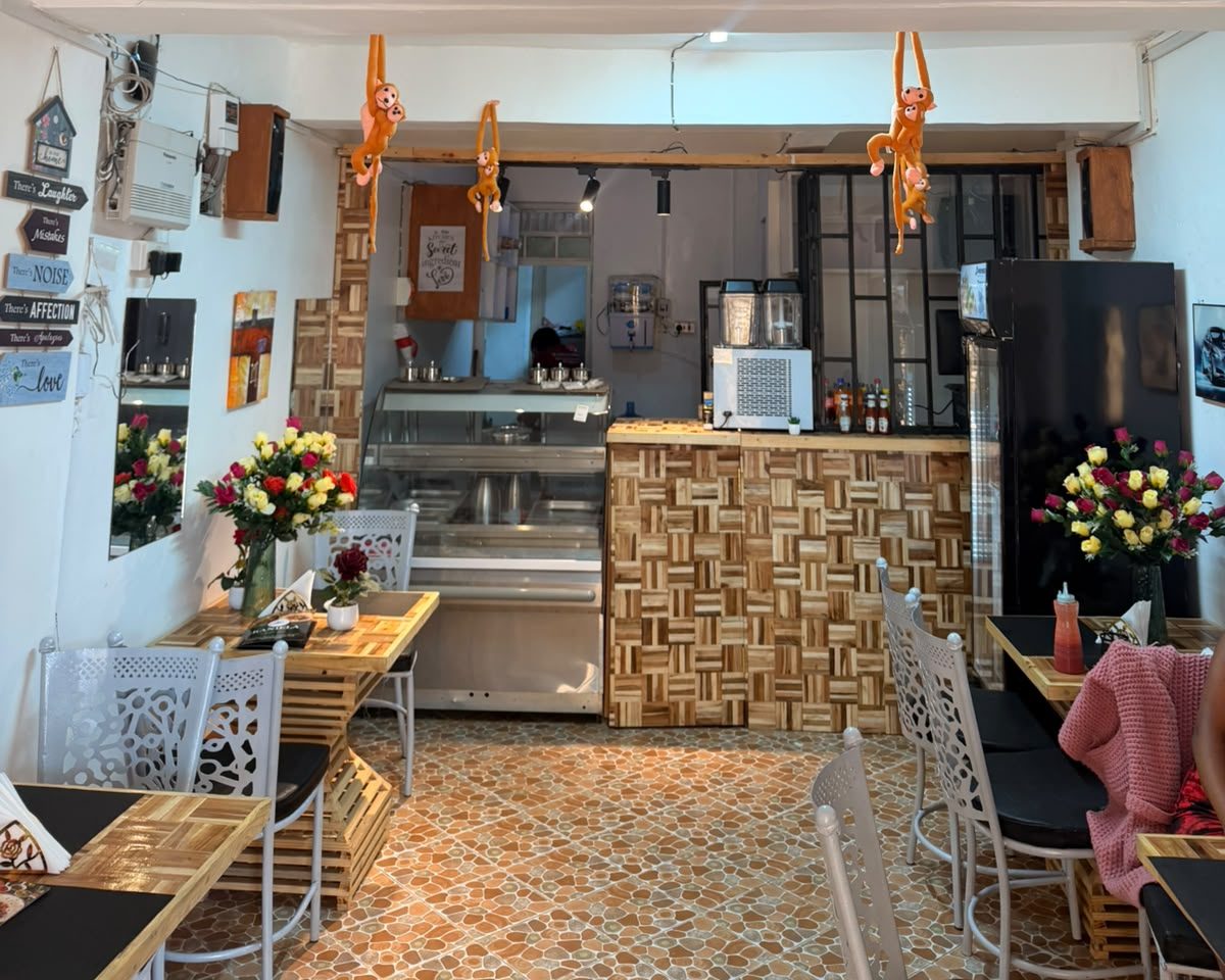 Inside Kaniella Grill Restaurant: wooden parquet counter, fresh roses on the tables and a glass food display